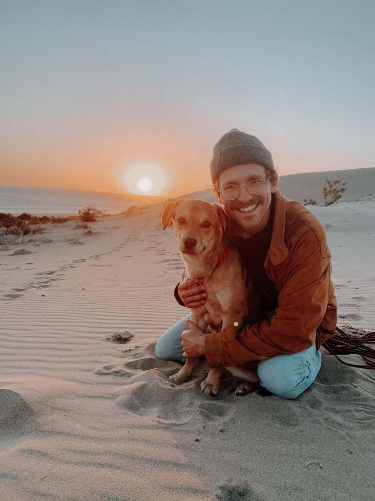 Marc und sein Hund Nalo sitzen bei Sonnenuntergang auf der Düne des Patara Strandes