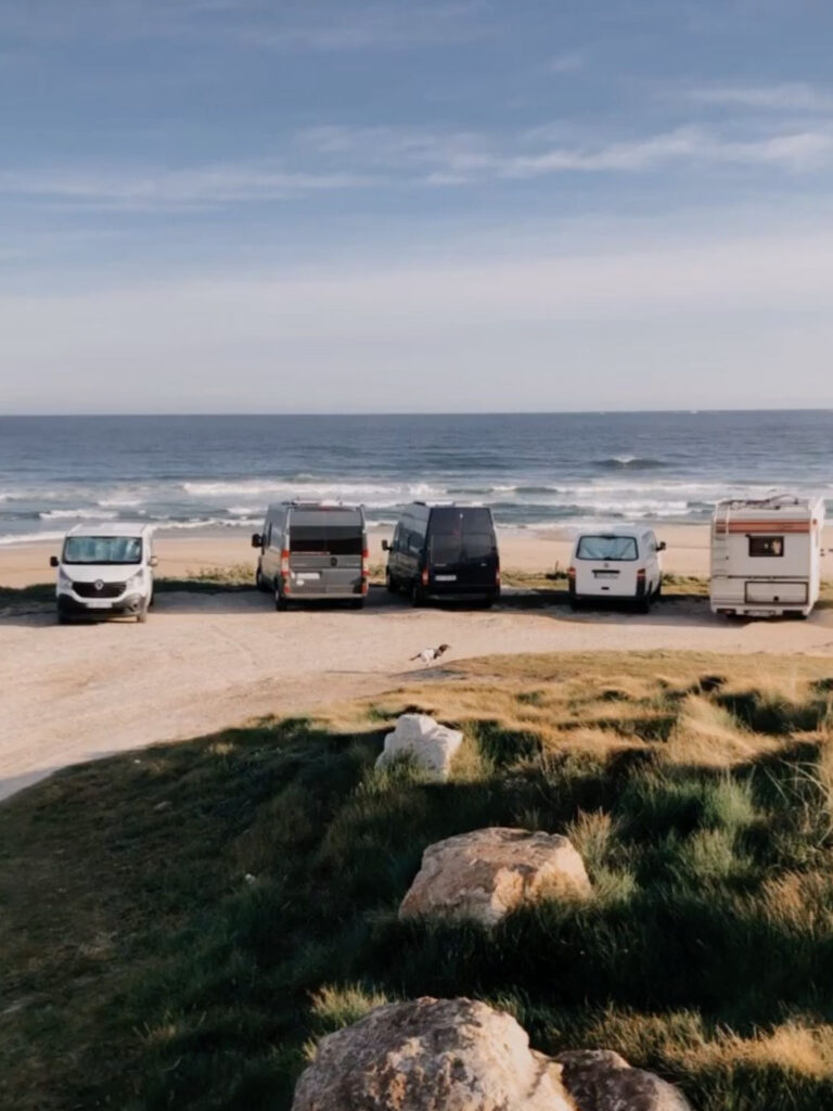 Campingfahrzeuge stehen auf einem Parkplatz an der Küste